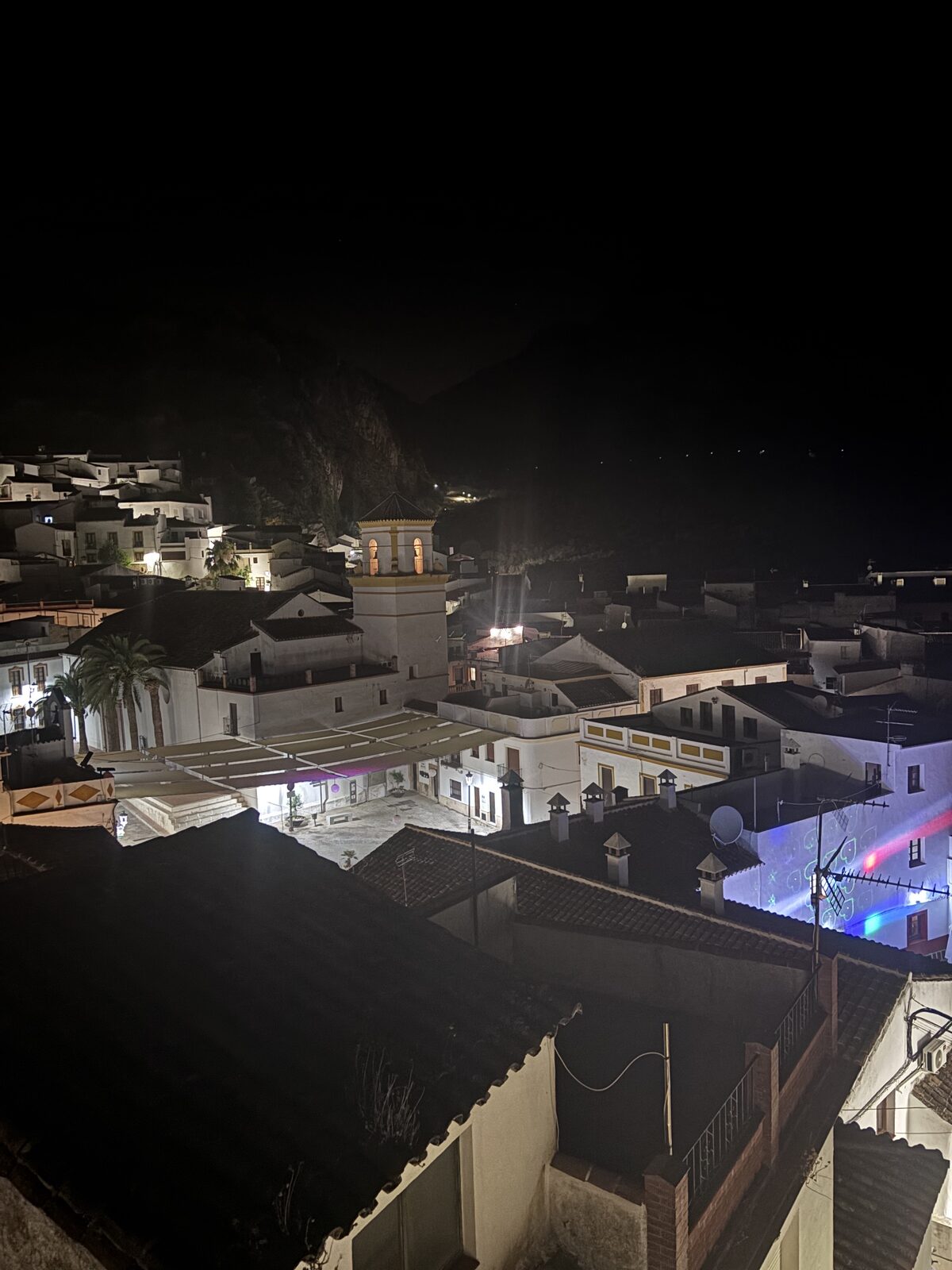 Vista nocturna del pueblo iluminado y el campanario desde la azotea