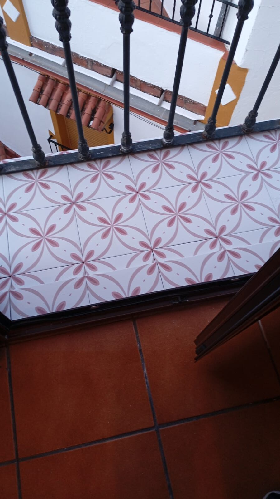 Balcón con suelo de azulejo de flores y barandilla de forja